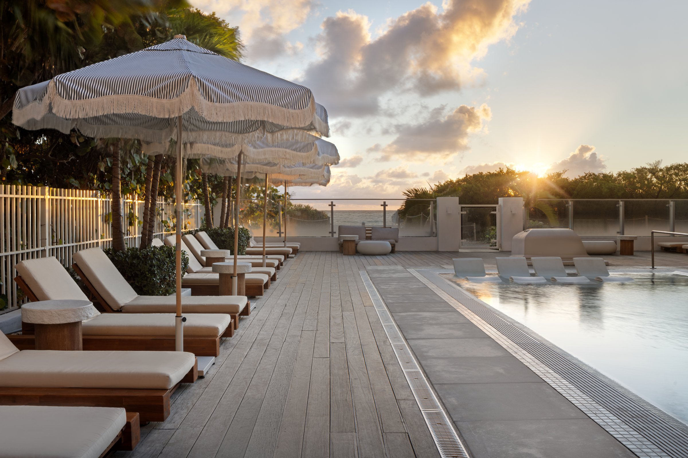 MB Hotel outdoor pool at dusk, the illuminated mb monogram glowing behind rows of loungers