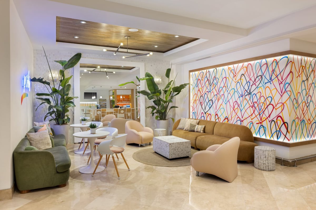 The MB Hotel lobby lounge, velvet and blush seating around a shell-inlaid table beneath the illuminated hand-painted hearts mural