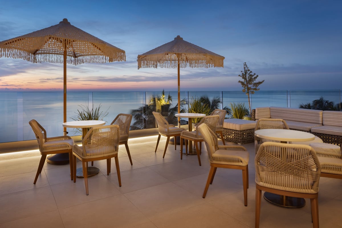 Rooftop lounge seating at dusk, cove lighting washing the terrace as the last colour leaves the sky over the ocean