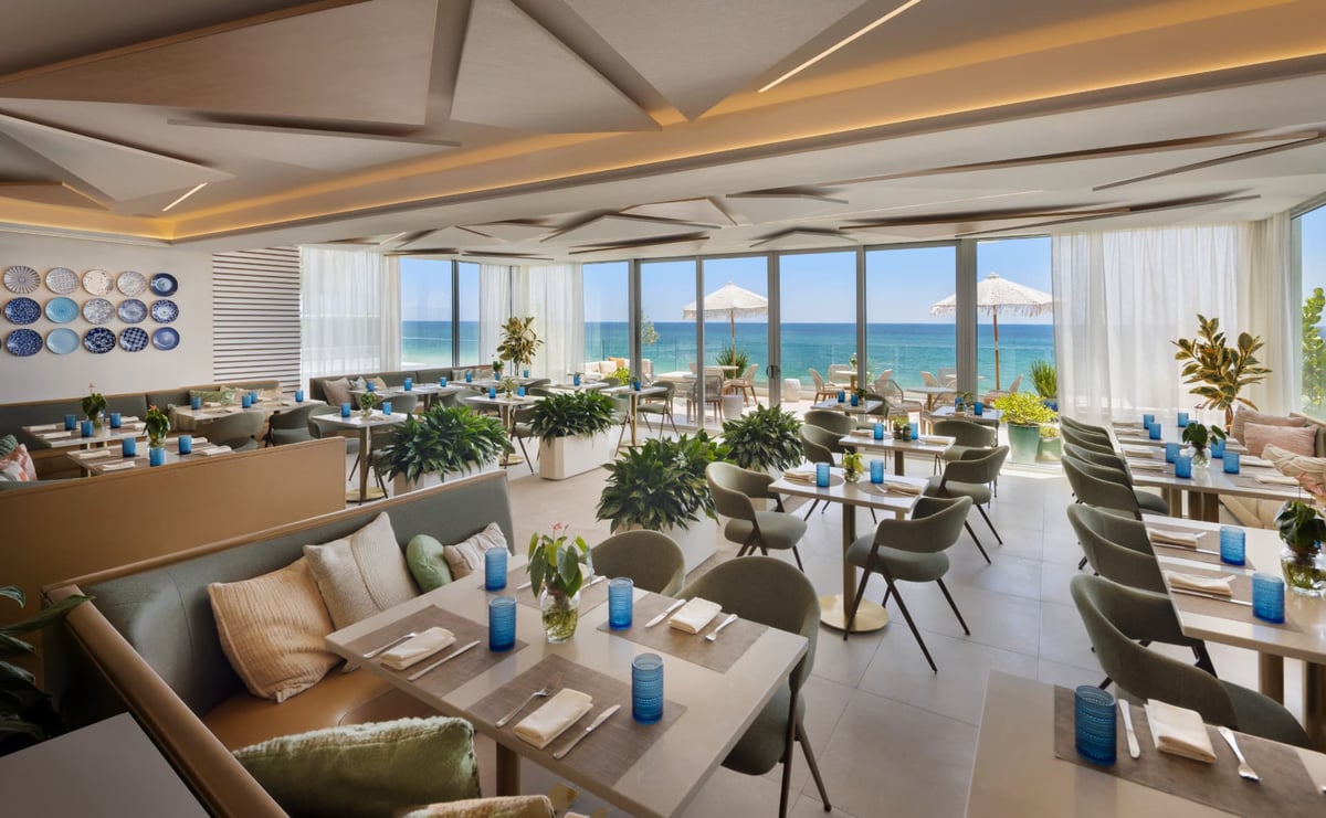 Kalypso in the middle of the day, laid tables and planters running the length of the room beneath the sculpted ceiling with the Atlantic on the horizon