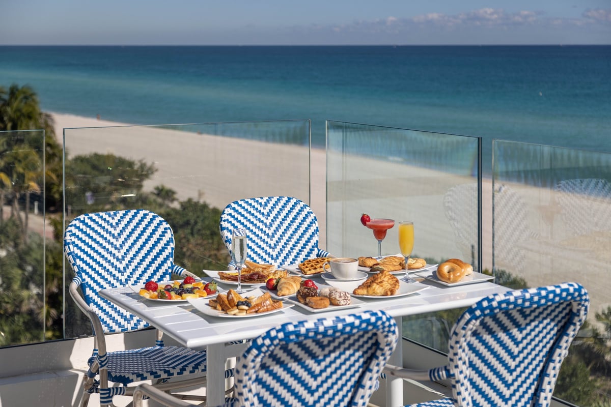 Breakfast on the MB Hotel rooftop — pastries, fruit and mimosas on a blue-and-white bistro table above the sand