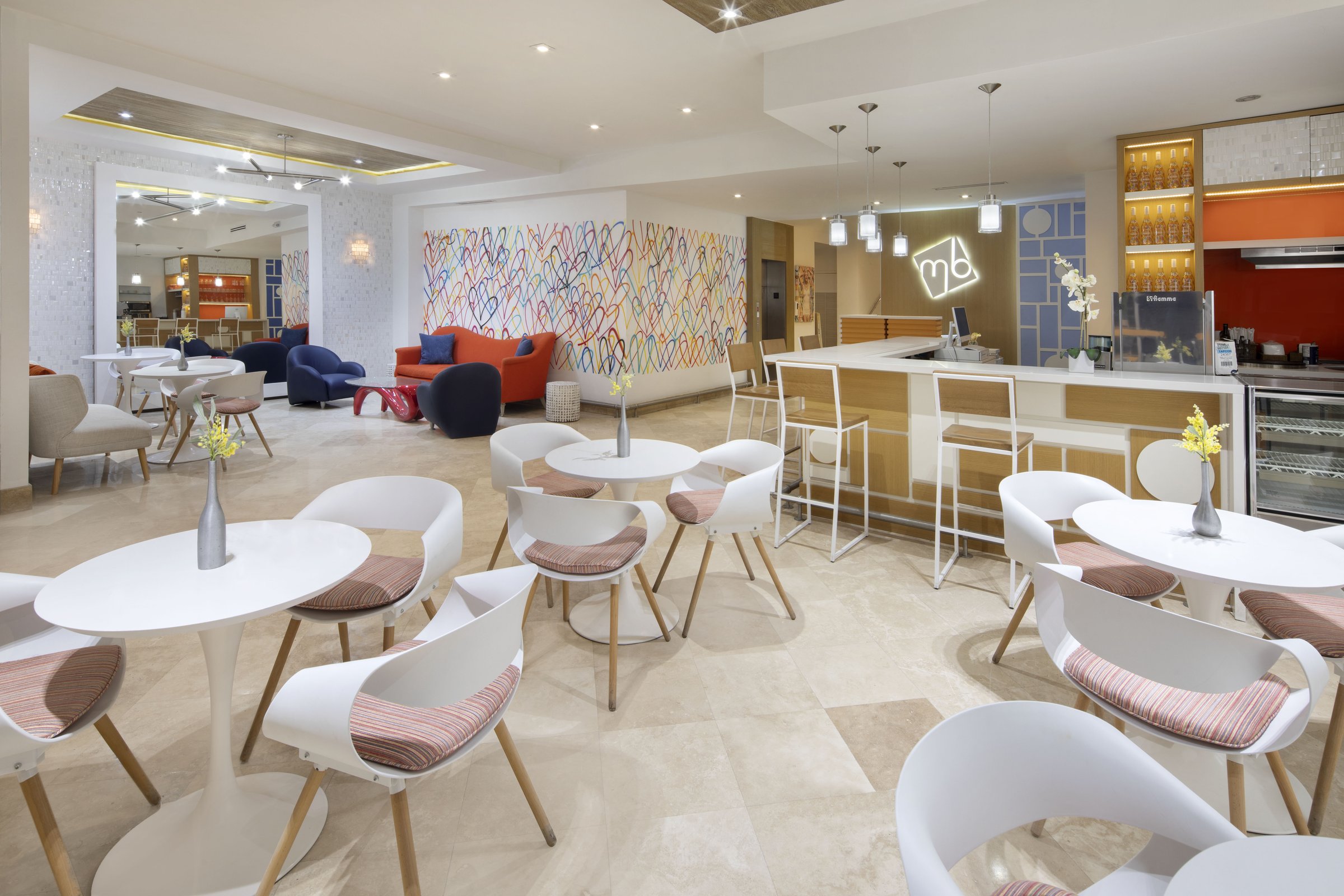 MB Hotel lobby, painted mural wall and lounge seating under warm ceiling light beside reception