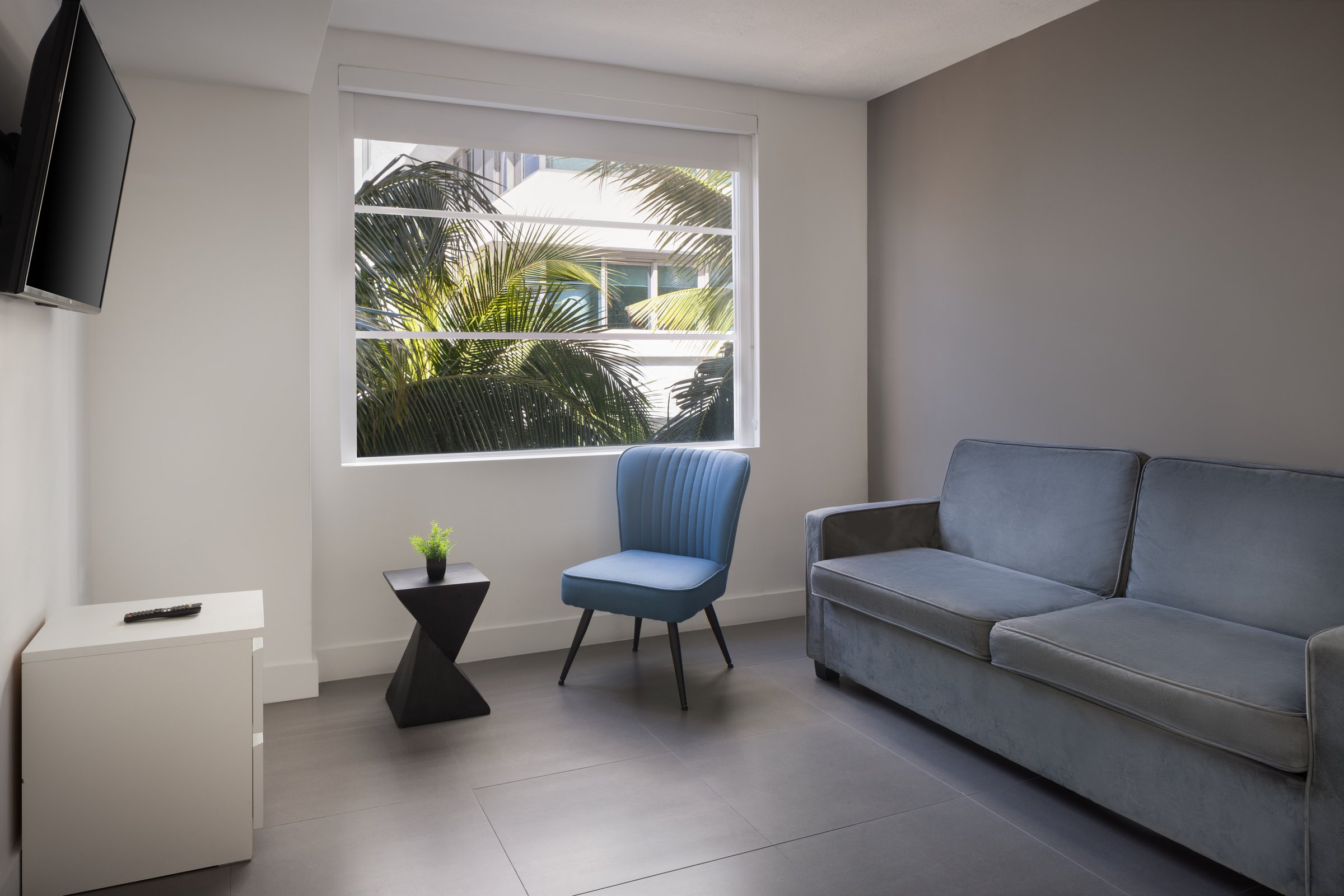 SNQ4 Deluxe Double Queen Suite living area, sofa and side table beside the balcony doors